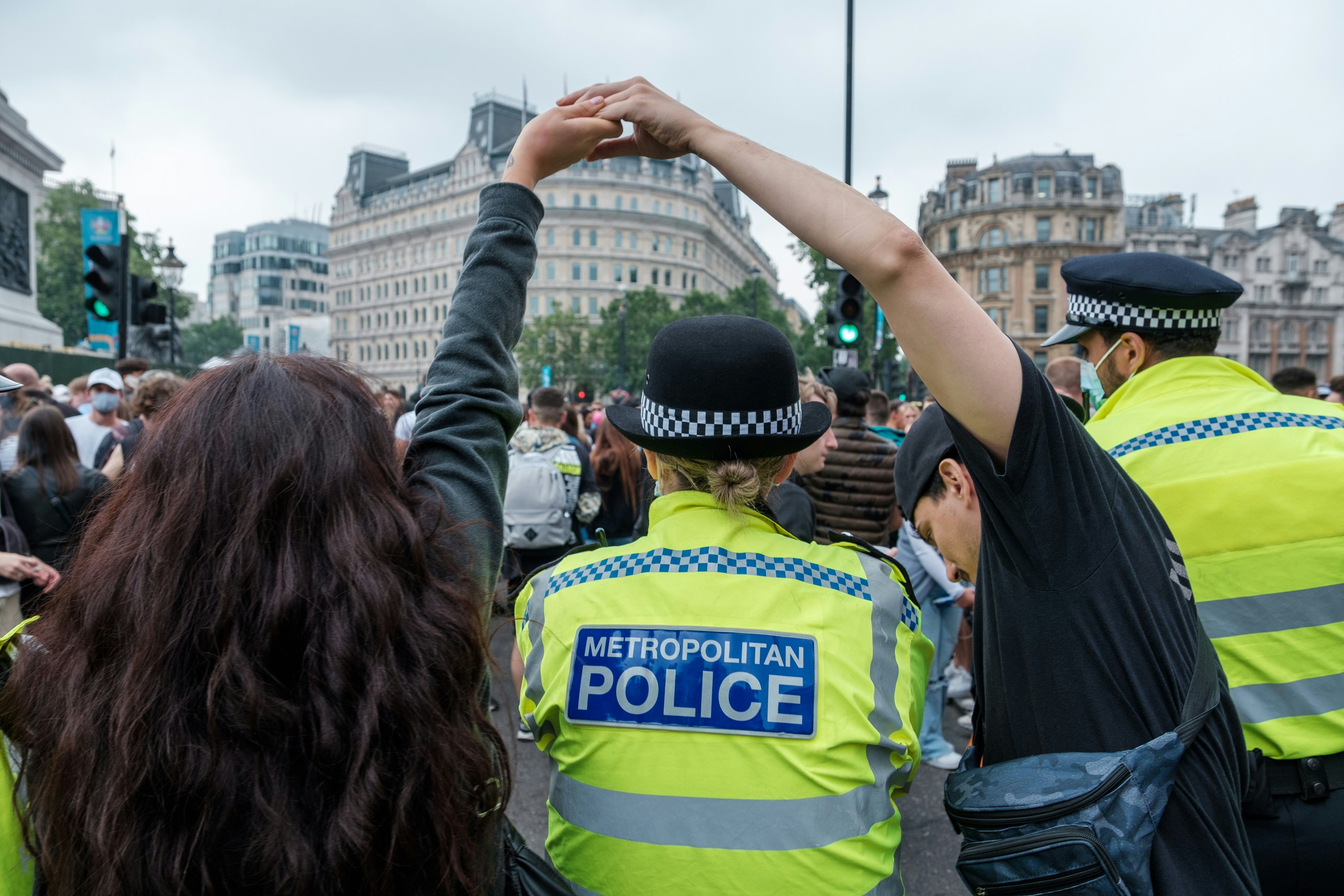 people in yellow and black uniform raising hands during daytime